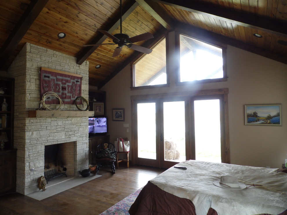 Großes Landhausstil Hauptschlafzimmer mit beiger Wandfarbe, hellem Holzboden, Kamin und Kaminumrandung aus Stein in Austin