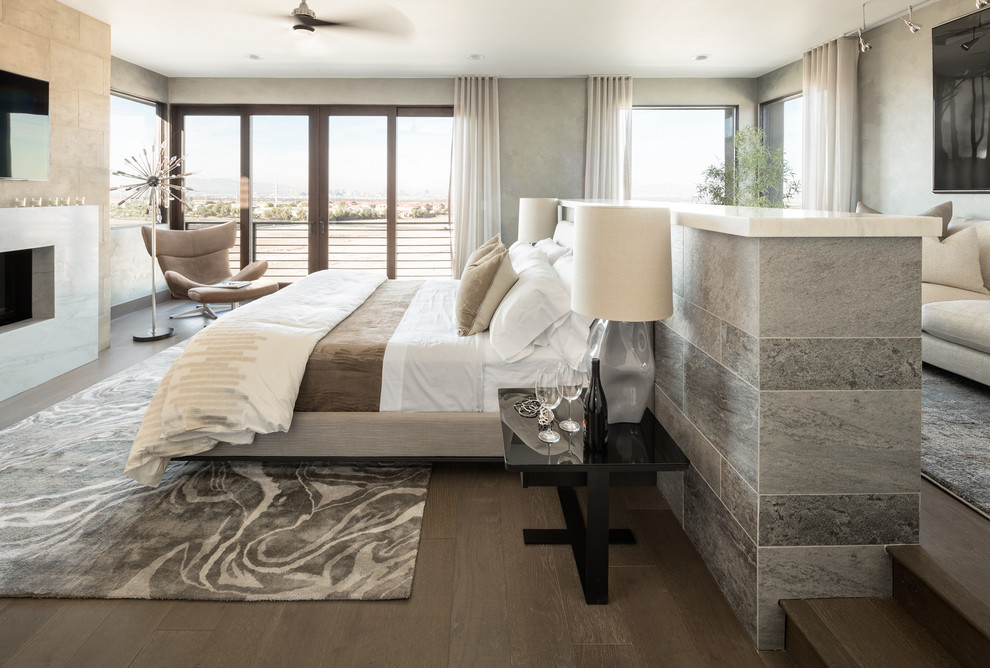This is an example of an expansive contemporary master and grey and brown bedroom in Las Vegas with grey walls, dark hardwood flooring, a standard fireplace and brown floors.