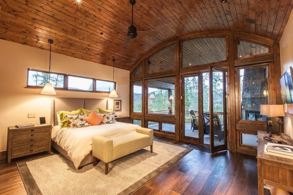 Diseño de dormitorio principal rural grande sin chimenea con paredes beige, suelo de madera en tonos medios y suelo marrón