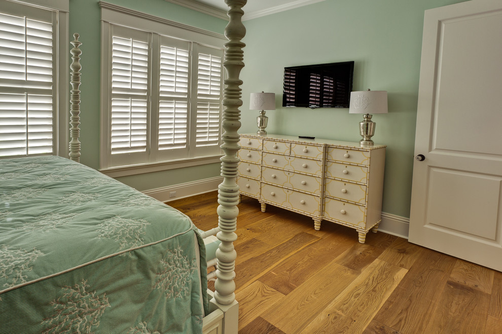 Modelo de dormitorio principal de estilo americano de tamaño medio con suelo de madera en tonos medios, paredes azules y suelo marrón