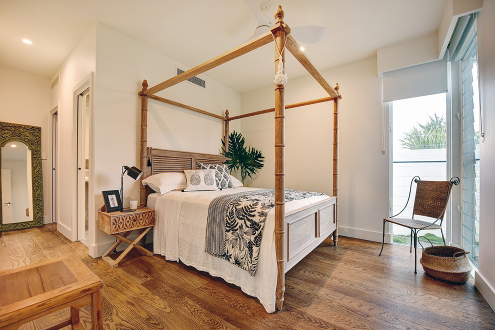 Imagen de dormitorio exótico con paredes blancas, suelo de madera en tonos medios y suelo marrón