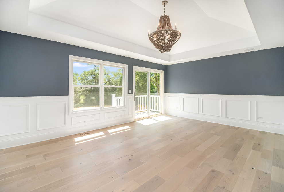 Design ideas for a large farmhouse master bedroom in Chicago with blue walls, light hardwood flooring, beige floors, a vaulted ceiling and wainscoting.