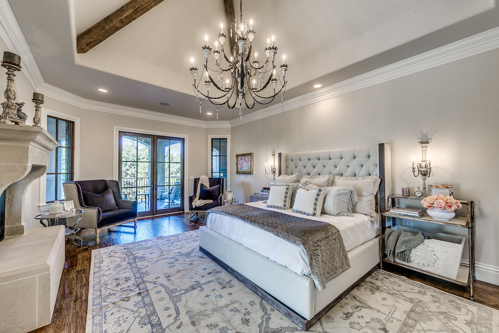 Example of a large transitional master brown floor and medium tone wood floor bedroom design in Oklahoma City with gray walls, a standard fireplace and a concrete fireplace