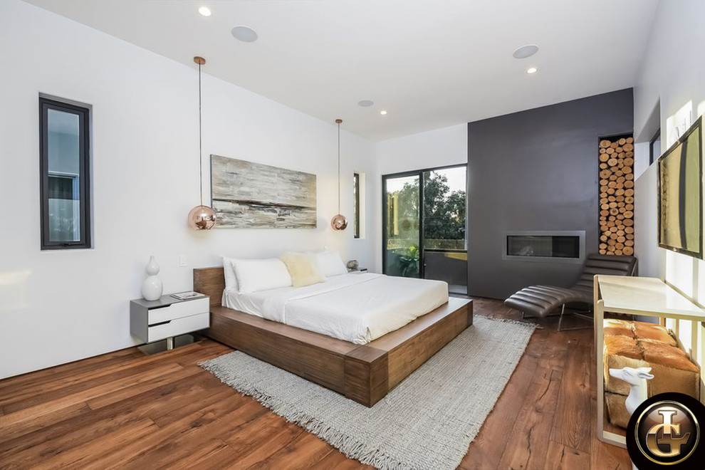 Large master bedroom in Los Angeles with white walls, dark hardwood flooring, a ribbon fireplace, a concrete fireplace surround and brown floors.
