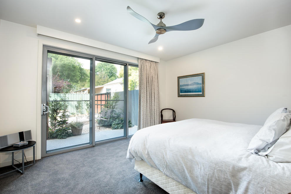 Modelo de dormitorio minimalista con paredes blancas, moqueta y suelo gris