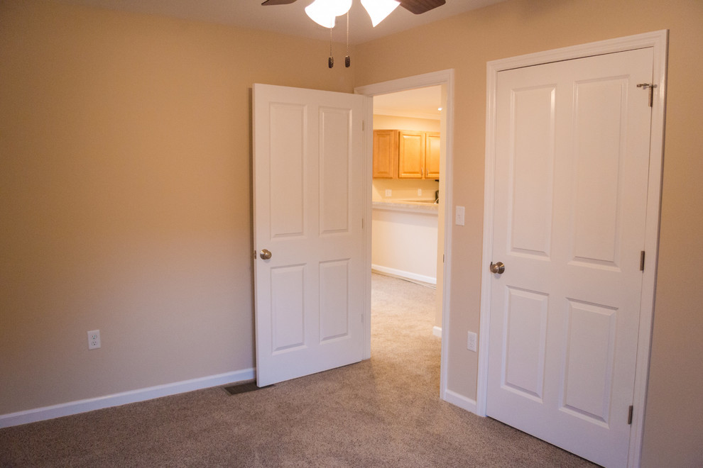Foto de habitación de invitados actual de tamaño medio sin chimenea con paredes beige y moqueta
