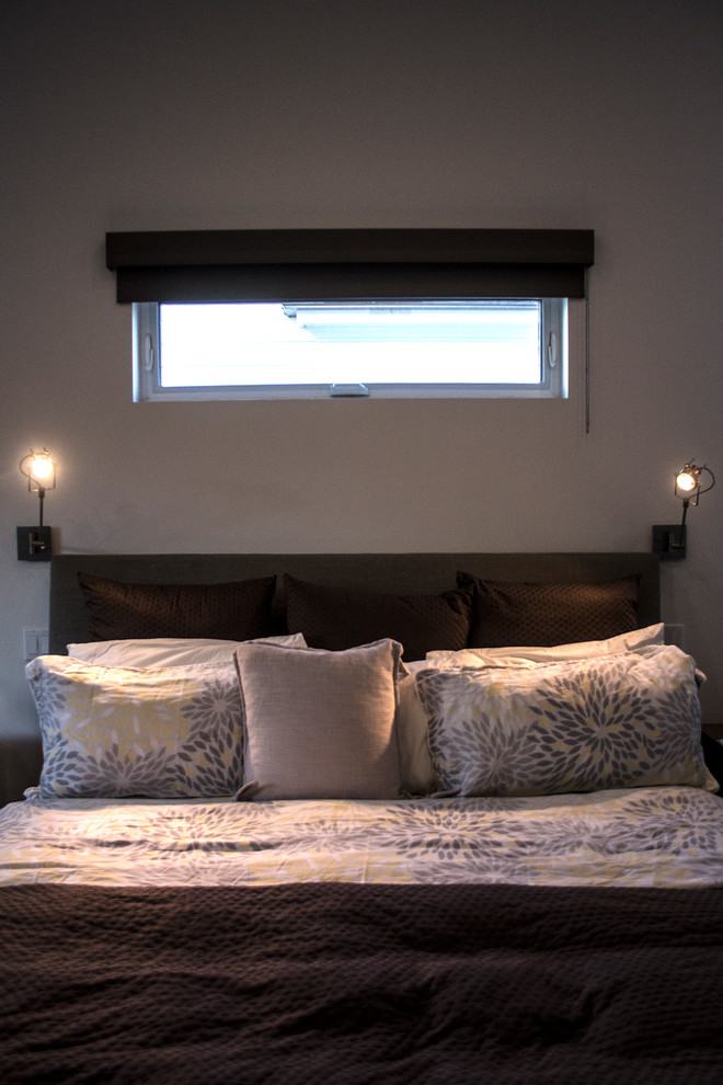 Imagen de dormitorio principal moderno grande sin chimenea con paredes beige y suelo de madera clara