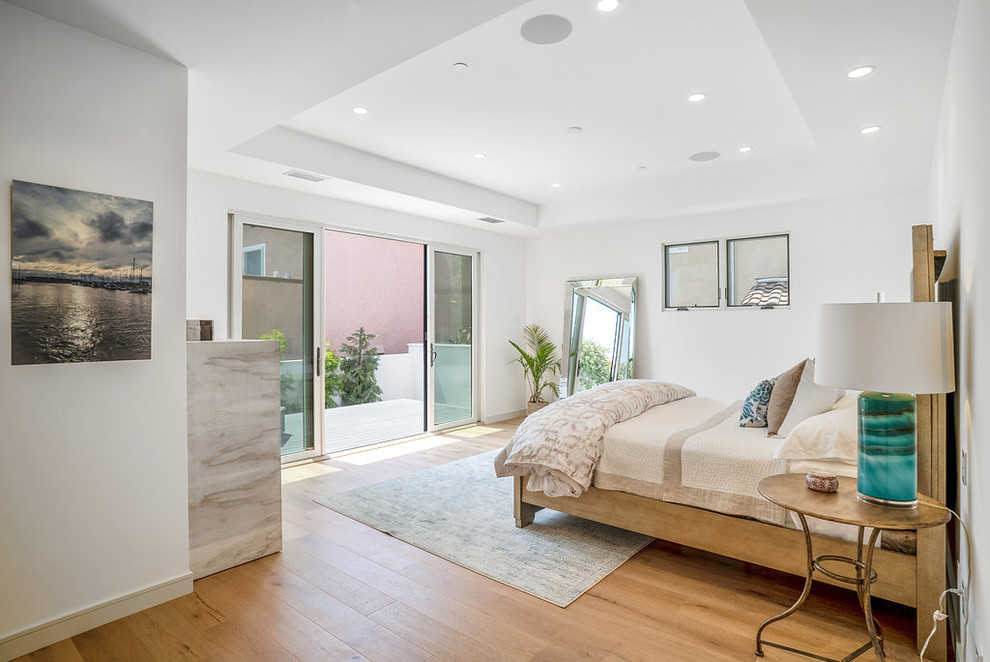 Ejemplo de habitación de invitados moderna grande con paredes blancas, suelo de madera clara y suelo marrón