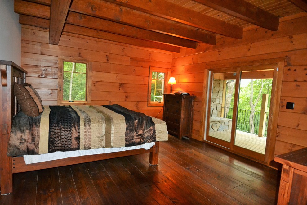 Mittelgroßes Uriges Hauptschlafzimmer mit beiger Wandfarbe, braunem Holzboden, Kamin, Kaminumrandung aus Stein und braunem Boden in Sonstige