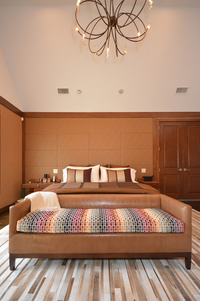 Стильный дизайн: хозяйская спальня среднего размера в современном стиле с оранжевыми стенами, темным паркетным полом, двусторонним камином, фасадом камина из камня и коричневым полом - последний тренд