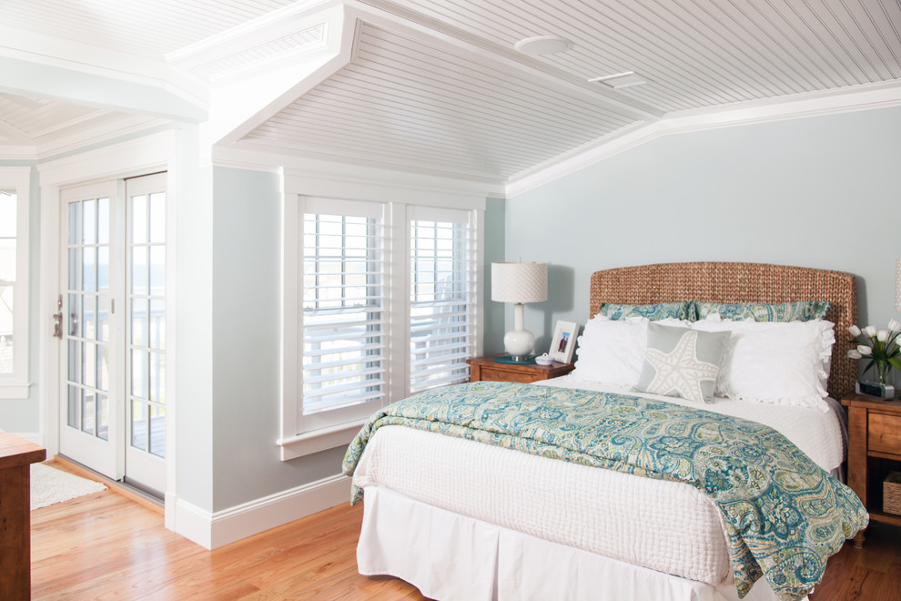Diseño de dormitorio principal costero de tamaño medio con paredes azules y suelo de madera en tonos medios