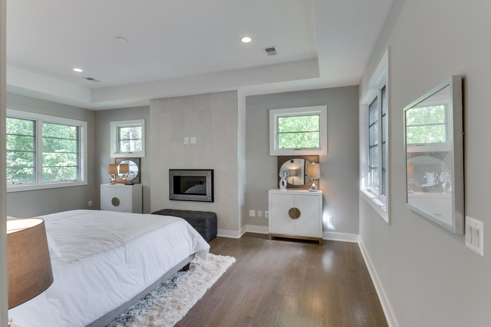 Cette photo montre une grande chambre parentale chic avec un mur beige, parquet clair, une cheminée standard, un manteau de cheminée en métal et un sol gris.