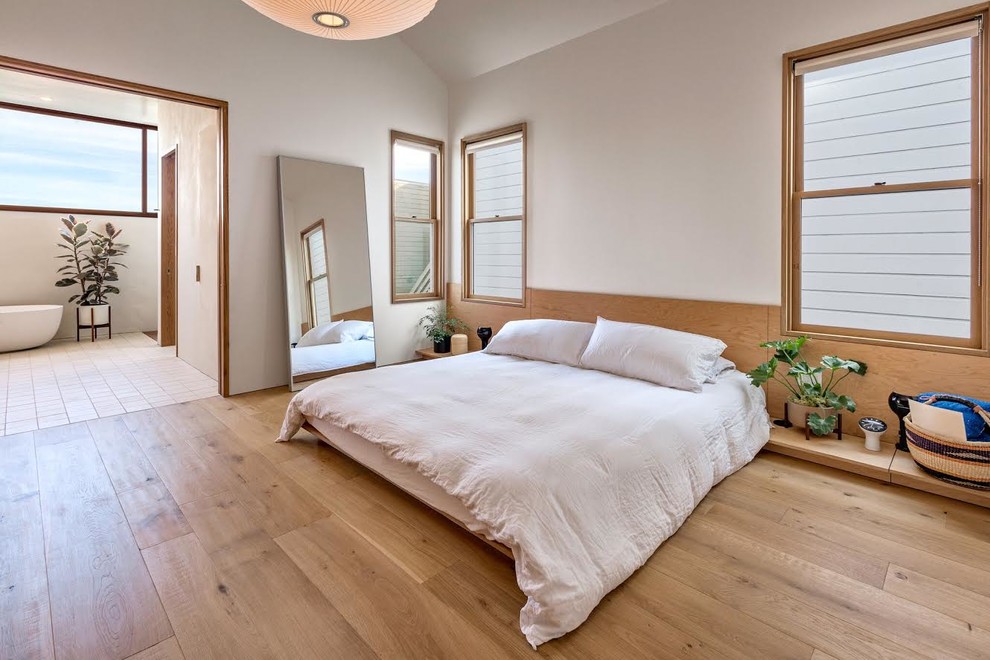 На фото: хозяйская спальня в скандинавском стиле с белыми стенами, светлым паркетным полом и бежевым полом