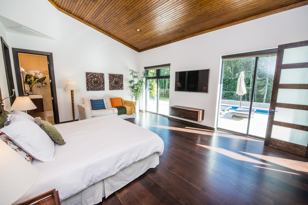 This is an example of a contemporary master bedroom in Raleigh with white walls and dark hardwood flooring.