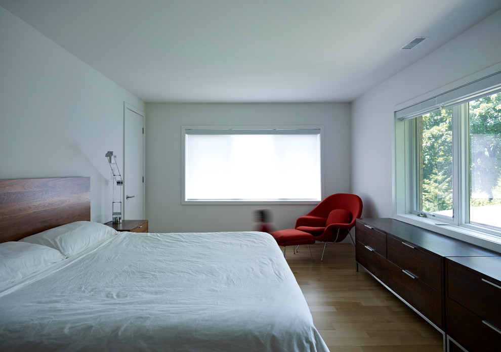 Cette photo montre une chambre moderne avec un mur blanc et parquet clair.