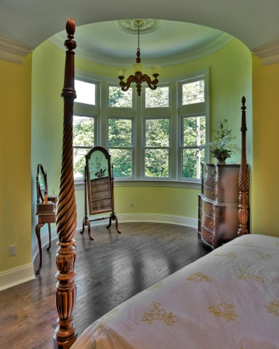 Cette image montre une petite chambre parentale victorienne avec un mur jaune et parquet foncé.