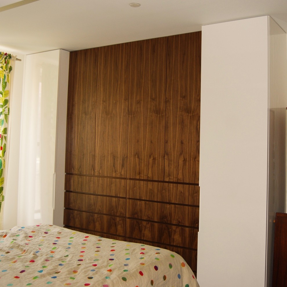 Réalisation d'une chambre parentale design de taille moyenne avec un mur blanc, aucune cheminée, un sol en bois brun et un sol marron.