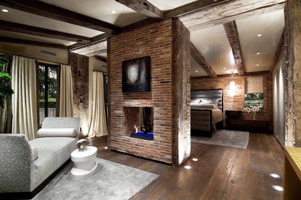 Diseño de dormitorio principal ecléctico grande con paredes beige, suelo de madera oscura, chimenea de doble cara y marco de chimenea de ladrillo