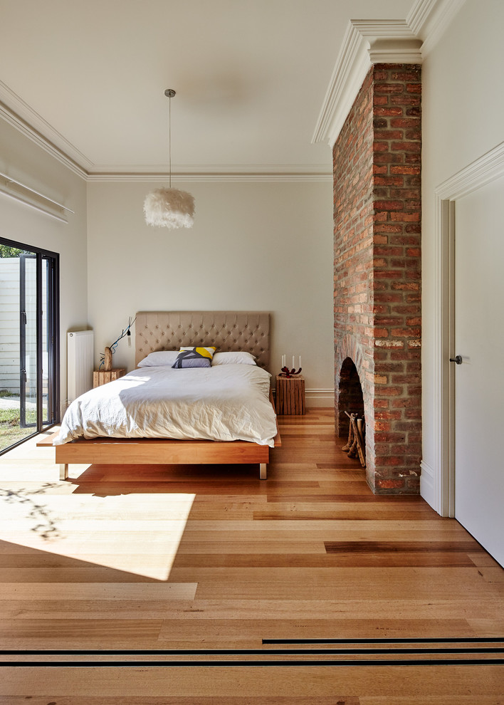 Diseño de dormitorio actual grande con paredes blancas y suelo de madera en tonos medios