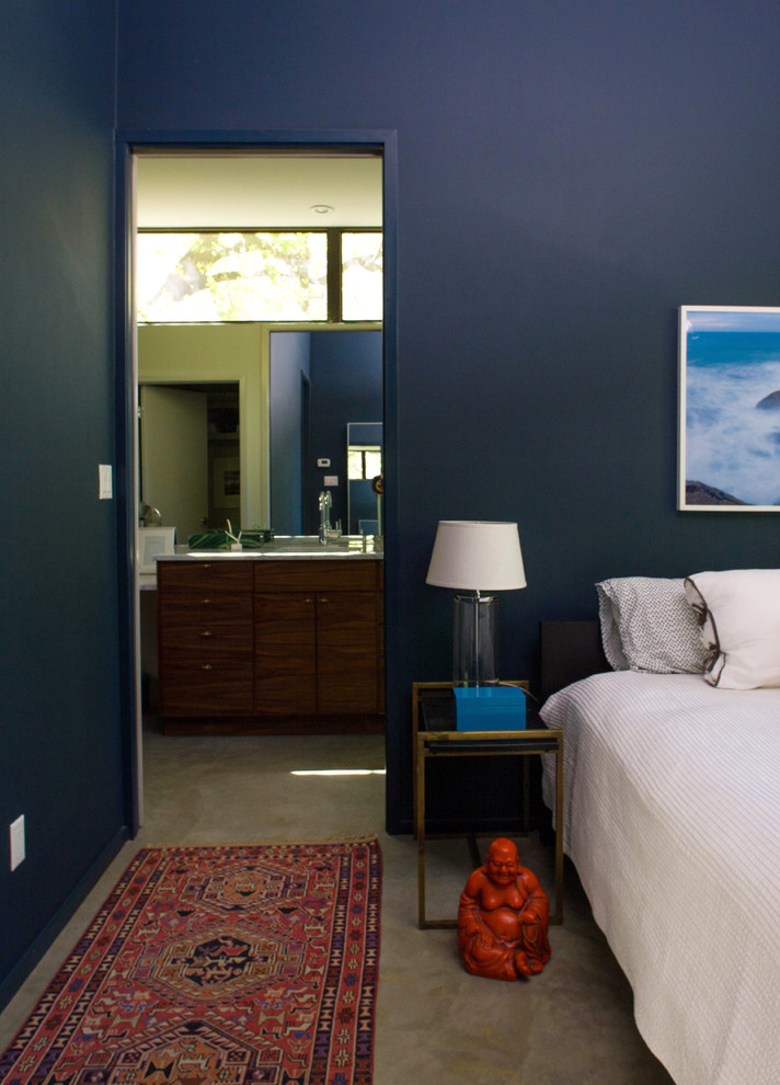 Réalisation d'une chambre parentale design avec un mur bleu et sol en béton ciré.