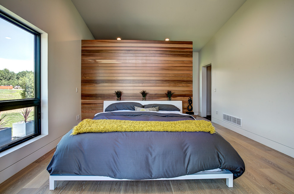 Modelo de dormitorio principal contemporáneo grande sin chimenea con paredes blancas y suelo de madera clara