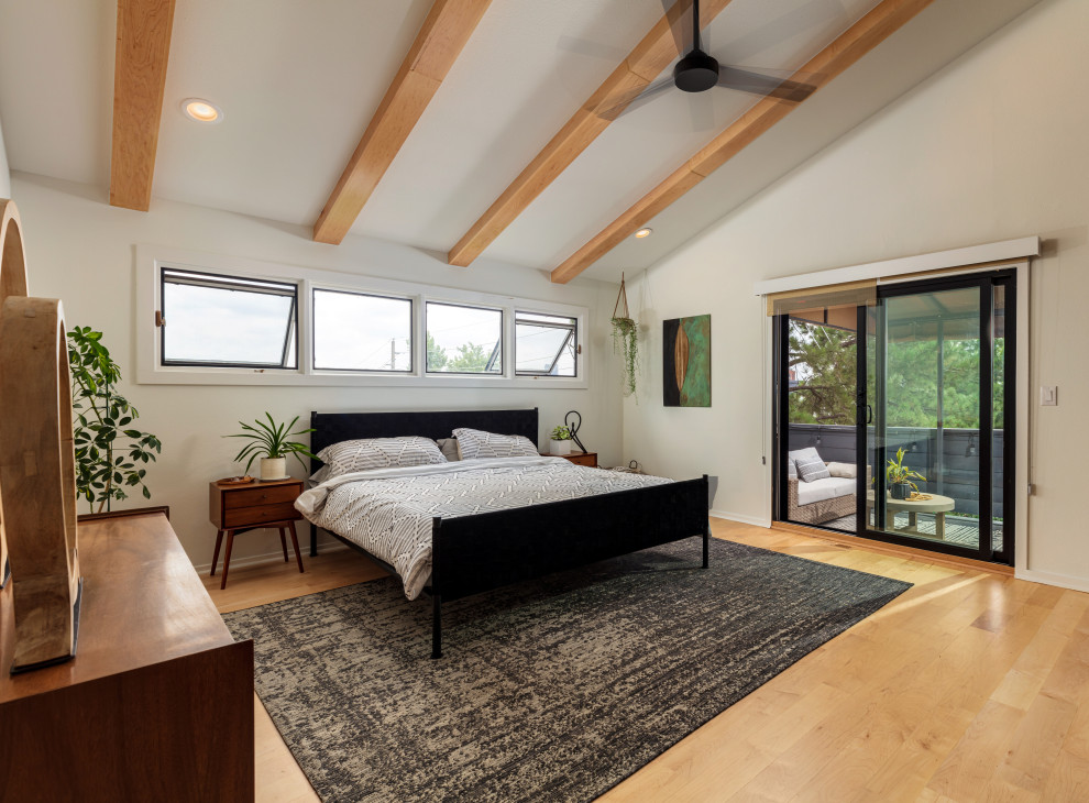 Immagine di una camera da letto minimal con pareti beige, pavimento in legno massello medio, pavimento marrone, travi a vista e soffitto a volta