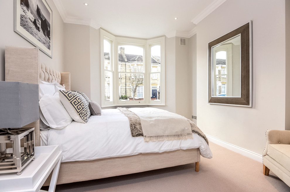 Photo of a traditional bedroom in London with beige walls, carpet and no fireplace.