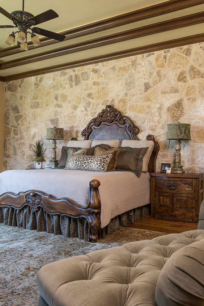 Стильный дизайн: огромная хозяйская спальня в классическом стиле с паркетным полом среднего тона, стандартным камином и фасадом камина из камня - последний тренд