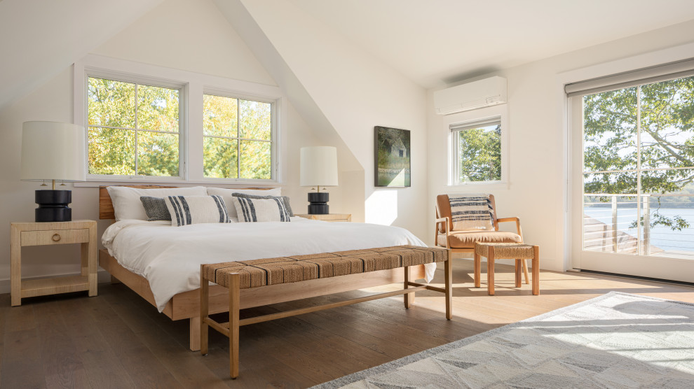Modelo de dormitorio abovedado costero con paredes blancas, suelo de madera en tonos medios y suelo marrón