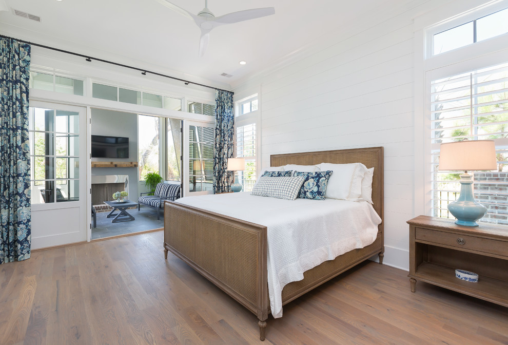 Ejemplo de dormitorio tipo loft de tamaño medio con paredes blancas, suelo de madera en tonos medios y suelo marrón
