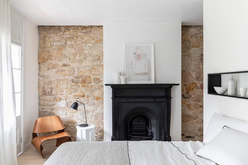 Cette image montre une chambre design avec un mur blanc, parquet clair, une cheminée standard et un sol beige.