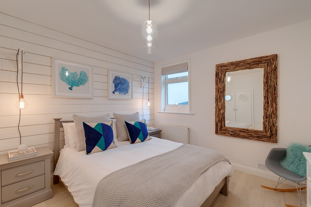 Diseño de dormitorio marinero sin chimenea con paredes blancas y suelo de madera clara