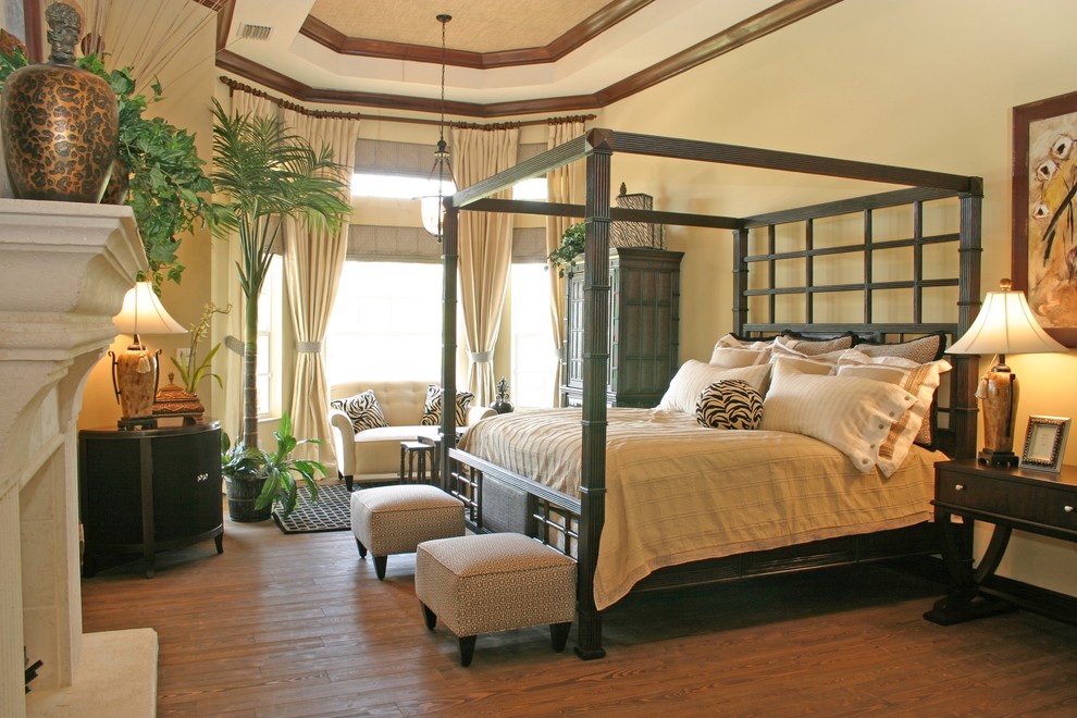 Modelo de dormitorio principal tropical con paredes beige, suelo de madera en tonos medios y todas las chimeneas