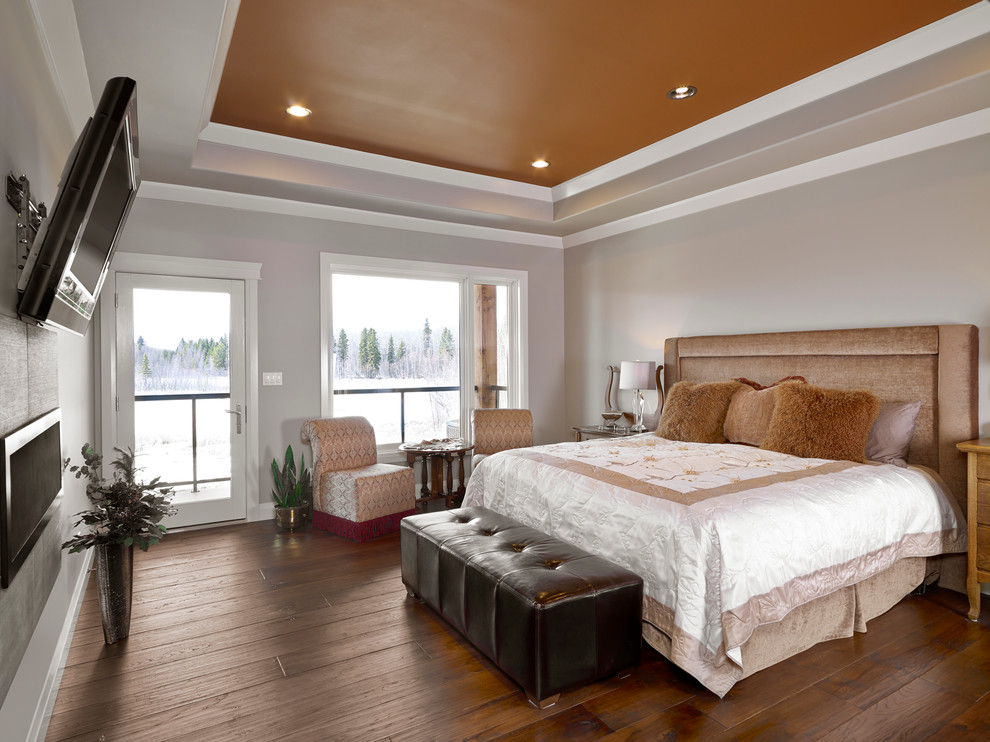 Modelo de dormitorio principal clásico grande con paredes grises, suelo de madera en tonos medios, chimenea lineal, marco de chimenea de metal y suelo marrón