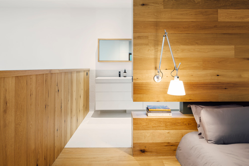 Mid-sized trendy master medium tone wood floor bedroom photo in Melbourne with white walls