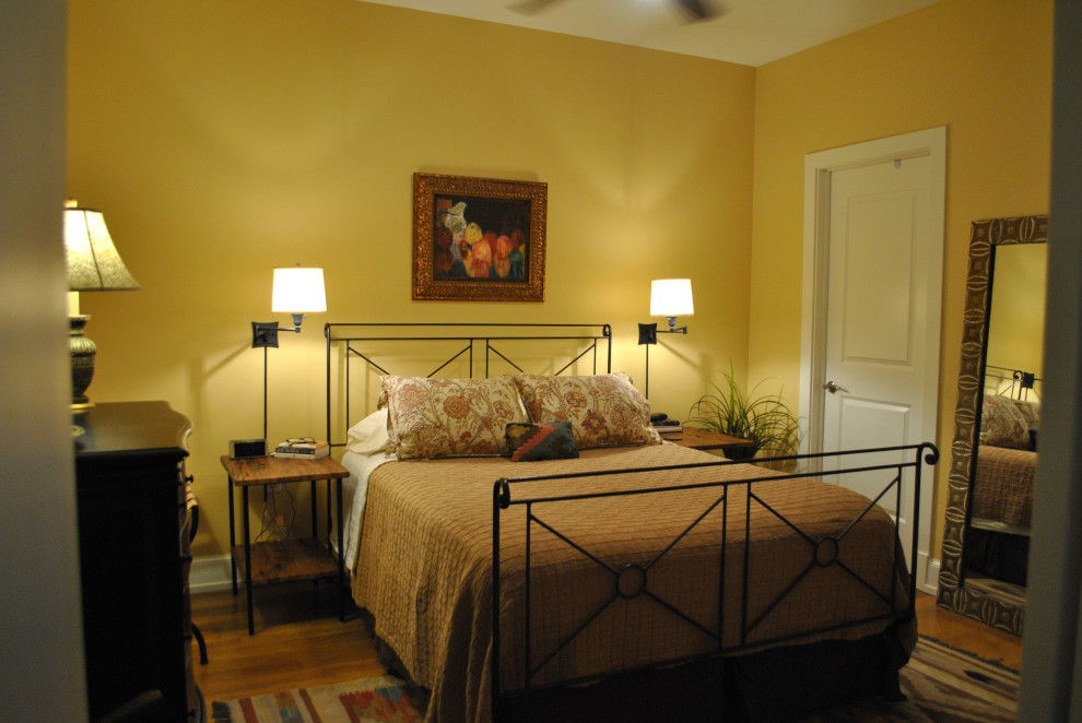 Cette photo montre une petite chambre parentale chic avec un mur jaune et parquet clair.