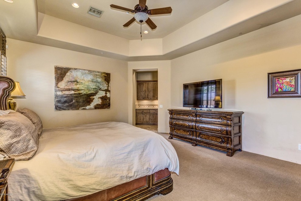 Inspiration for a large mediterranean master carpeted and beige floor bedroom remodel in Phoenix with beige walls
