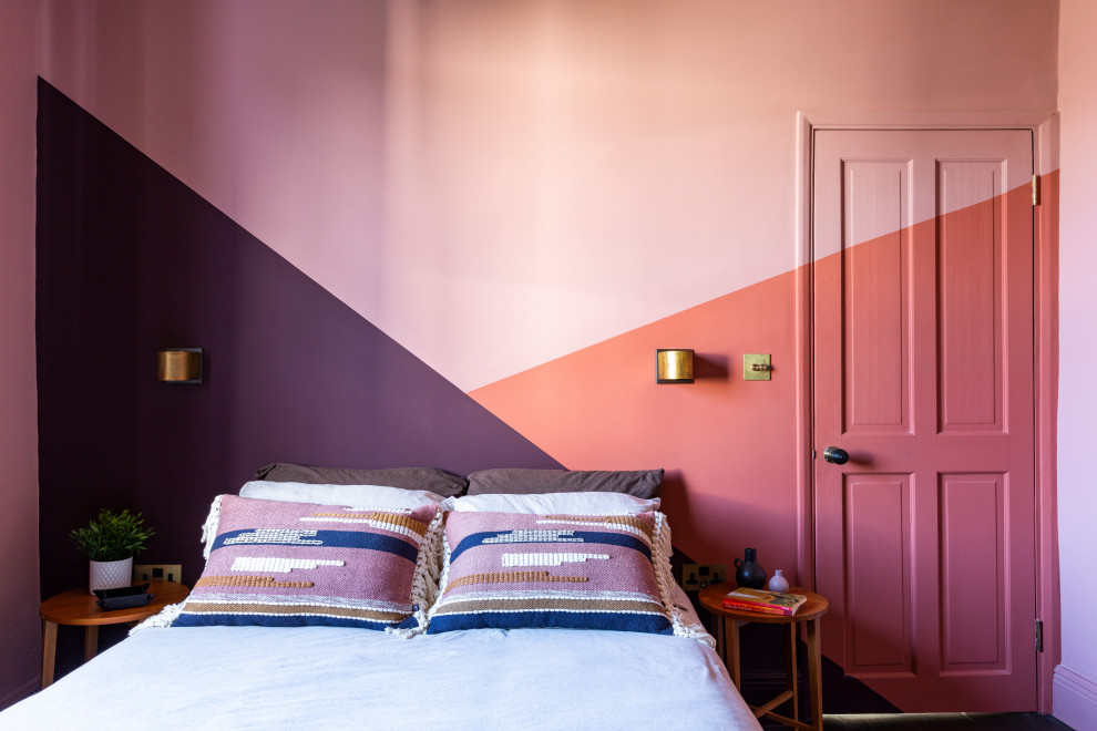 This is an example of a medium sized eclectic guest bedroom in London with pink walls, dark hardwood flooring, no fireplace and brown floors.