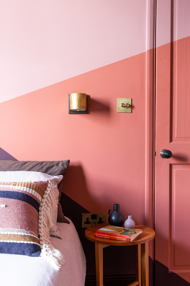 This is an example of a medium sized bohemian guest bedroom in London with pink walls, dark hardwood flooring, no fireplace and brown floors.