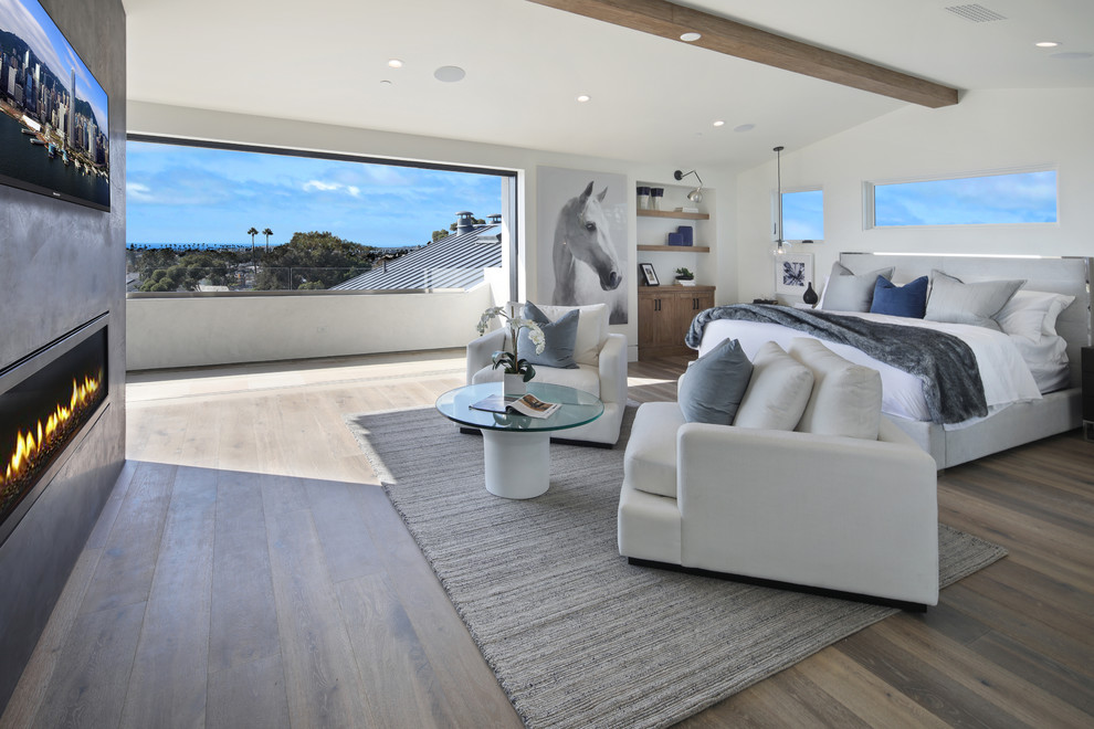 Schlafzimmer mit weißer Wandfarbe, braunem Holzboden, Gaskamin, Kaminumrandung aus Beton und braunem Boden in Orange County