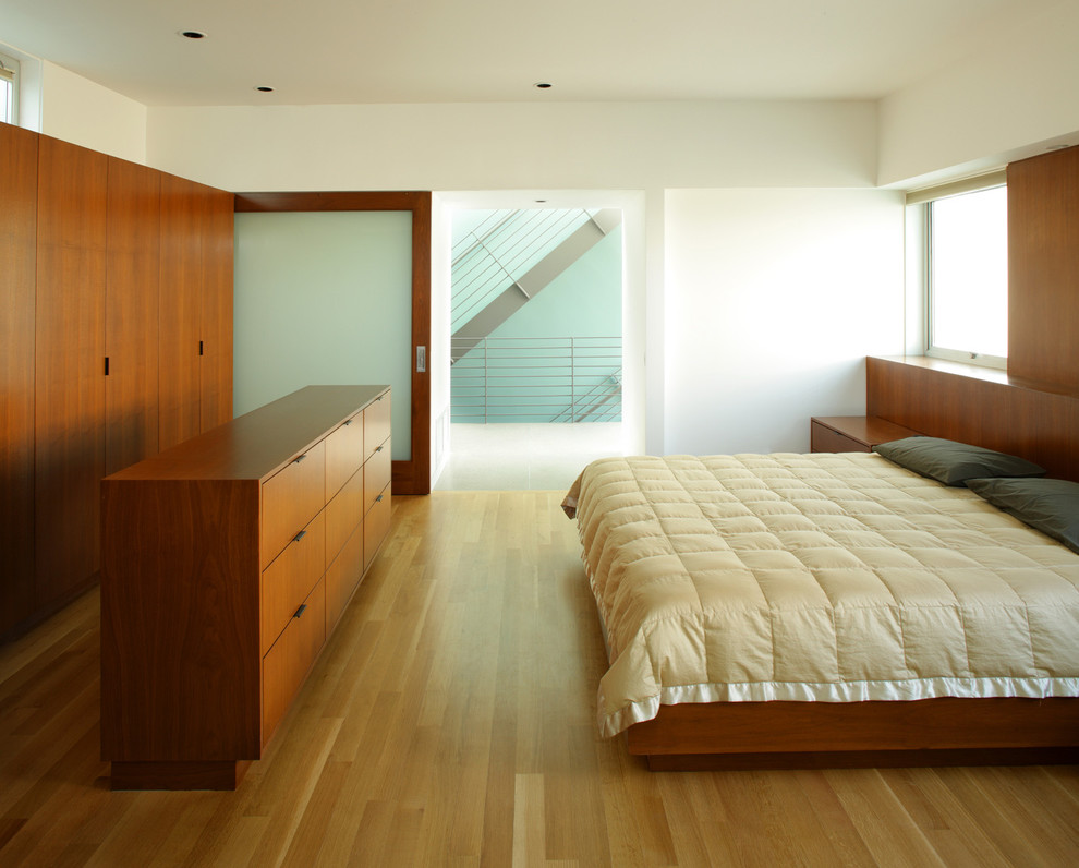 Diseño de dormitorio minimalista con paredes blancas y suelo de madera en tonos medios