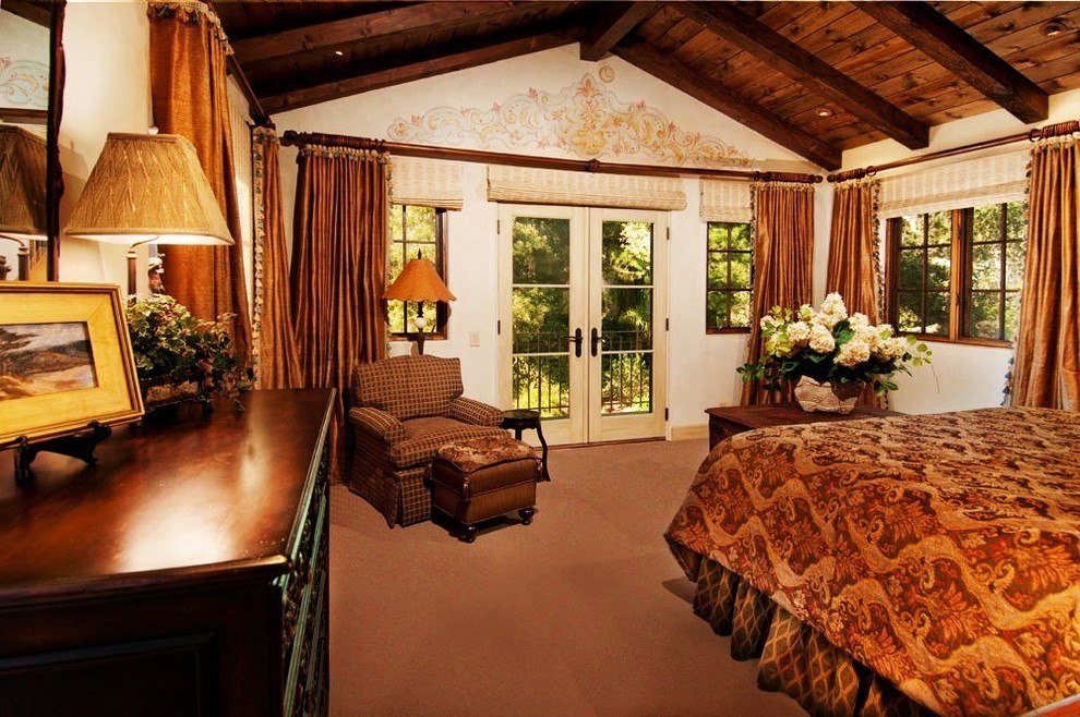 シアトルにある広い地中海スタイルのおしゃれな主寝室 (ベージュの壁、ライムストーンの床、石材の暖炉まわり、ベージュの床)