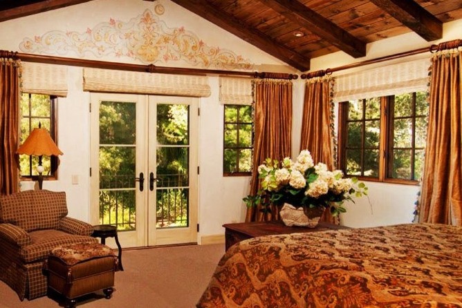 シアトルにある広い地中海スタイルのおしゃれな主寝室 (ベージュの壁、ライムストーンの床、石材の暖炉まわり、ベージュの床) のレイアウト