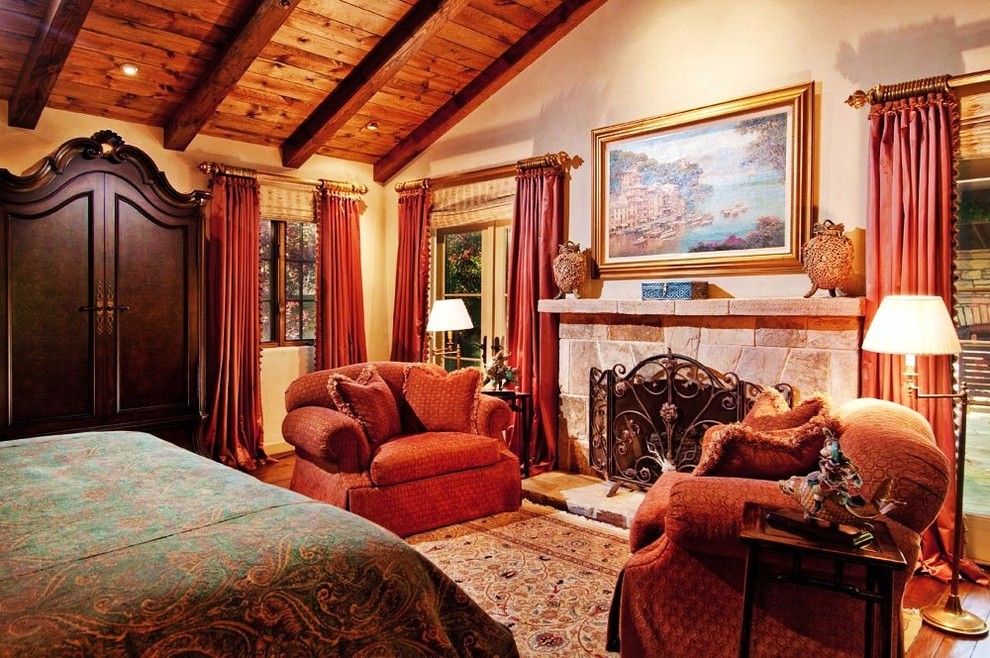 Example of a large tuscan master limestone floor and beige floor bedroom design in Seattle with a stone fireplace and beige walls
