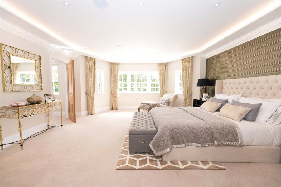 Large traditional master bedroom in Surrey with grey walls and carpet.