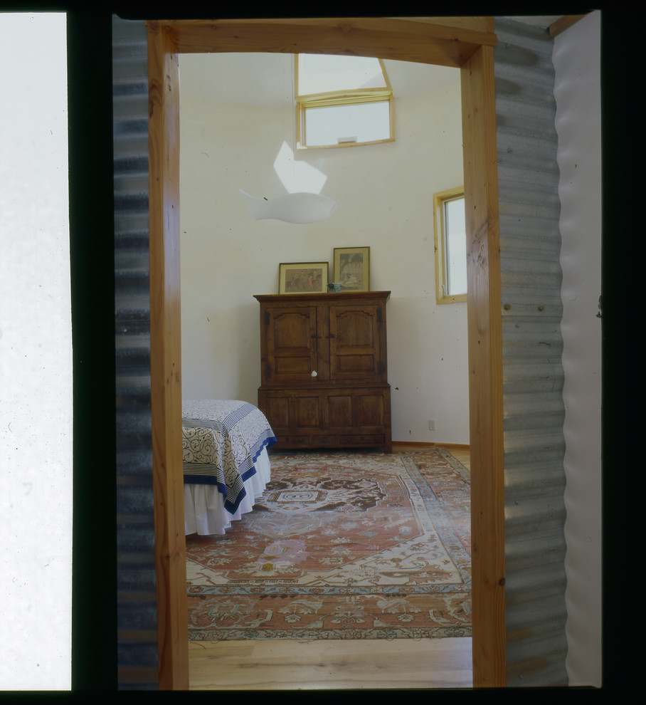 Modelo de habitación de invitados industrial de tamaño medio sin chimenea con paredes blancas y suelo de madera clara