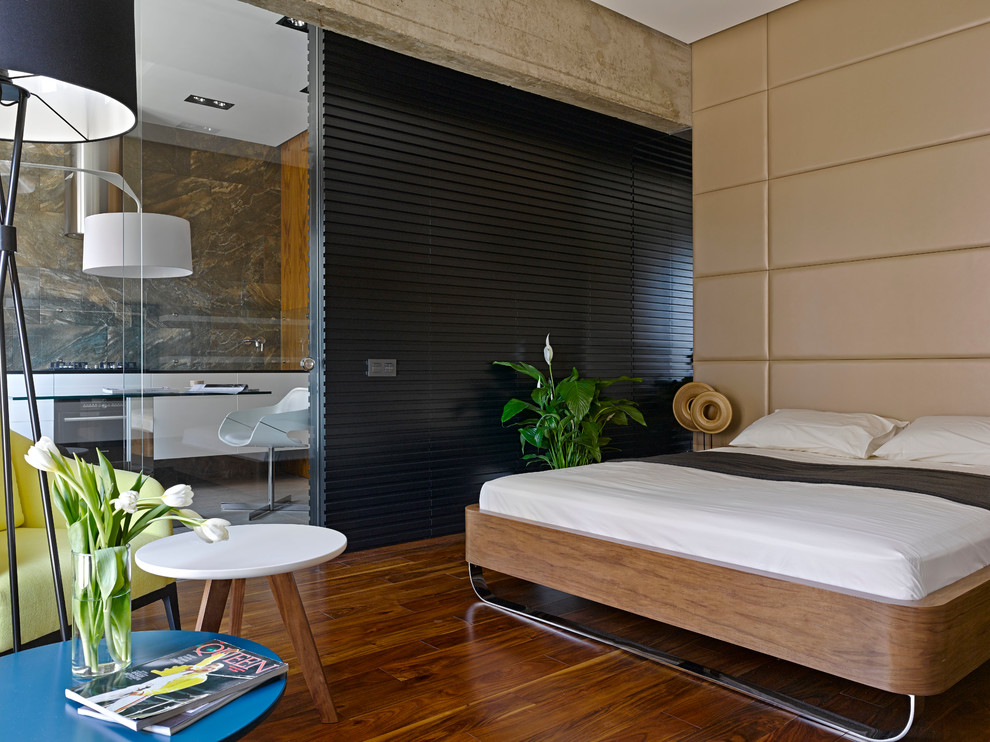 Immagine di una camera matrimoniale design con pareti beige, pavimento in legno massello medio e pavimento marrone