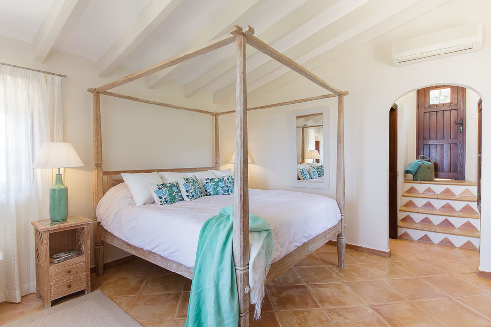 Immagine di una camera matrimoniale mediterranea di medie dimensioni con pareti bianche, pavimento in terracotta e nessun camino