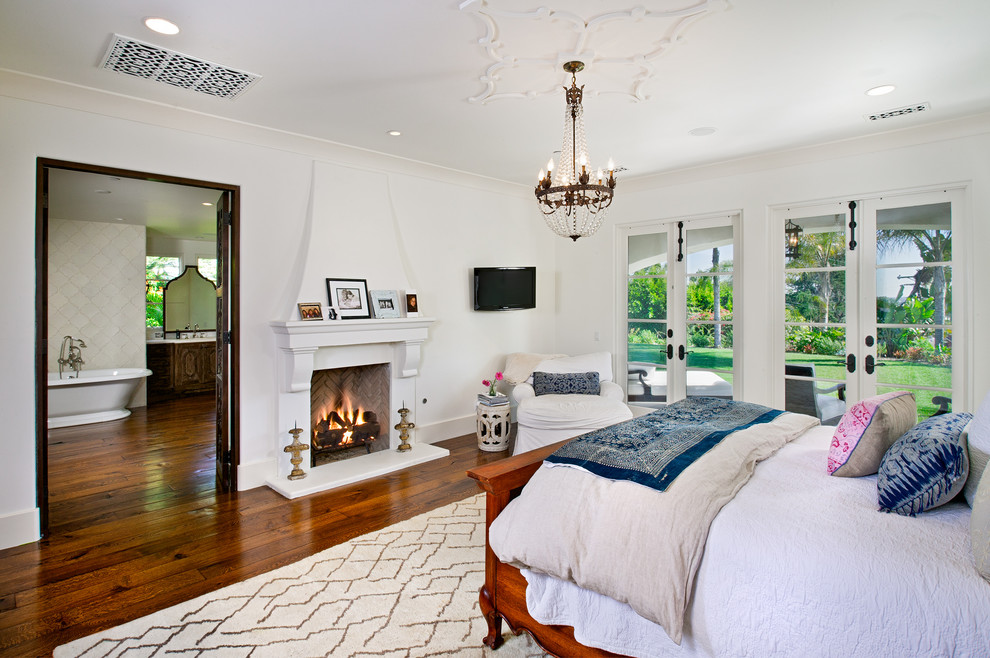 Mediterranes Schlafzimmer mit weißer Wandfarbe, dunklem Holzboden und Kamin in San Diego