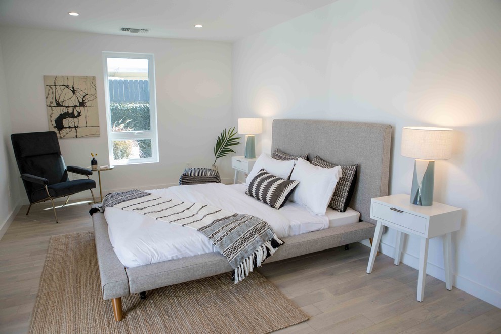 Aménagement d'une chambre parentale moderne de taille moyenne avec un mur blanc, parquet clair et un sol marron.